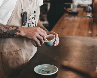 Barista bereitet Kaffee mit Milch zu