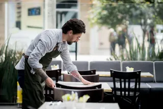 Ein Servicemitarbeiter deckt Tische in einem Restaurant ein