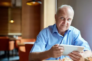 Ein älterer Gastronom mit einer iPad-Kasse mit integriertem Kassenbuch.