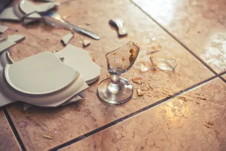 Verbrochenes Glas und Geschirr auf einem Fliesenboden.