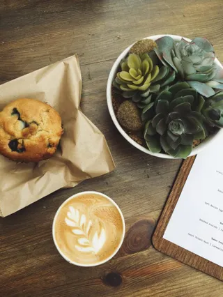 Ein Kaffee, ein Muffin und eine Speisekarte auf dem Tisch