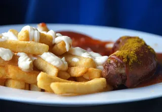 Ein Imbissteller mit Currywurst und Pommes