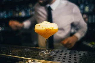 Ein zubereiteter Cocktail in einer Bar mit Bartender im Hintergrund