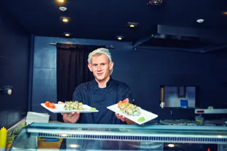 Ei Koch in Arbeitskleidung zeigt Sushi in seinem Restaurant