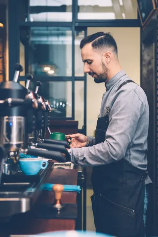 Ein Barista in einem Café bereitet in Arbeitskleidung einen Espresso zu