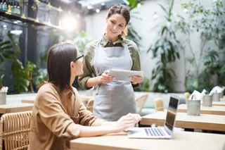 Eine freundliche Servicekraft bedient einen Gast mit einer iPad-Kasse!