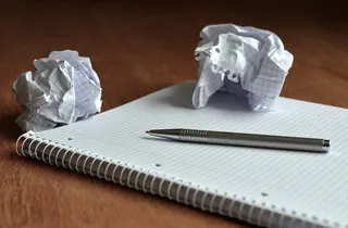Zerknüllte Papierfetzen und ein Schreibblock mit Stift