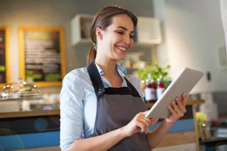 Gastronomin tippt lächelnd auf einem iPad-Kassensystem.