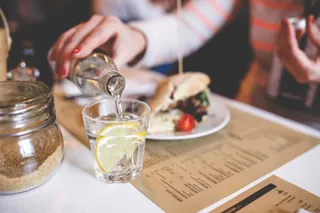 Ein Restaurant-Gast schenkt sich ein Mineralwasser ein