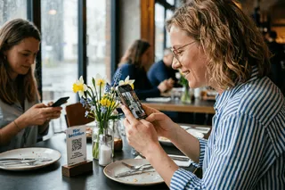 Digitale Speisekarte im Restaurant – Gast scannt QR-Code am Tisch
