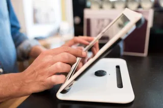 Hände eines Gastronomen, die eine iPad Kasse bedienen.