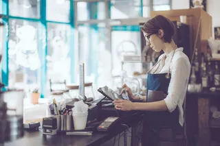 Gastronomin hinter Tresen mit einer iPad-Kasse.