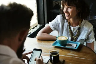 Pärchen im Café, er ist auf Facebook, sie trinkt Kaffee